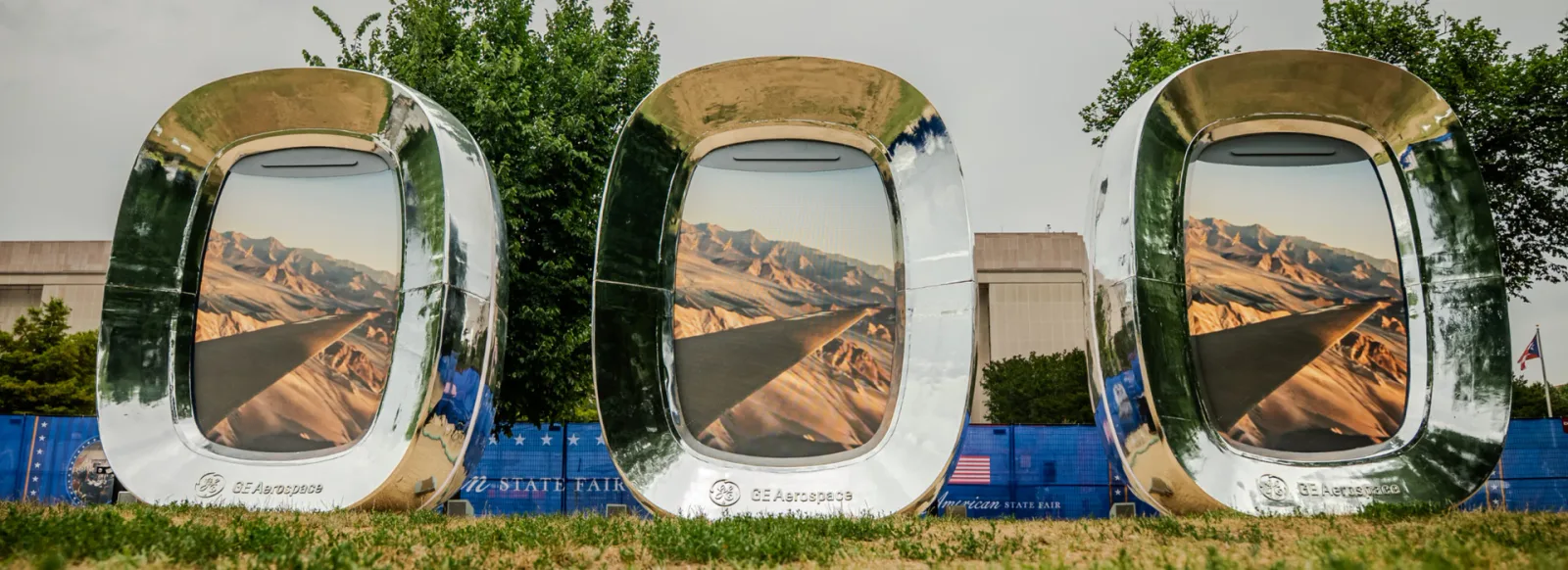 Three complete mirrored window-shaped LED display enclosures in an outdoor landscape.