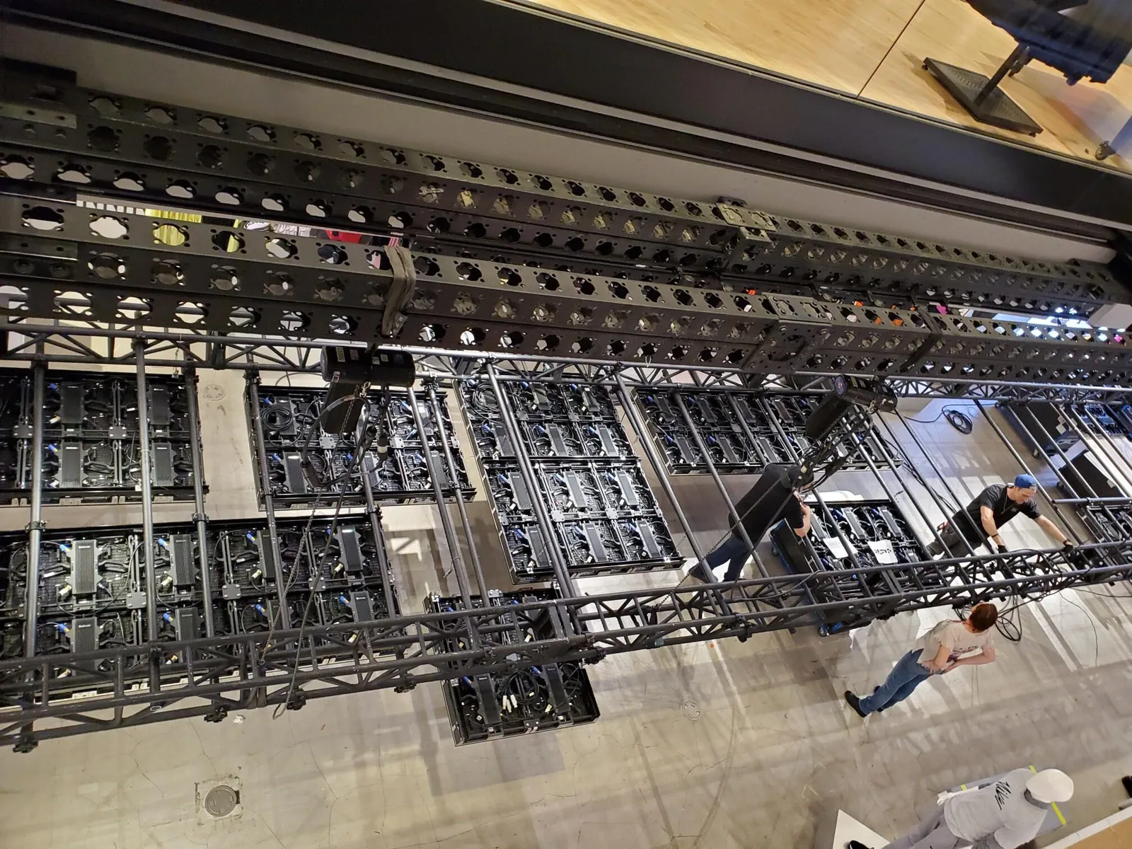 People working around the rear structure and wiring of a large display installation.