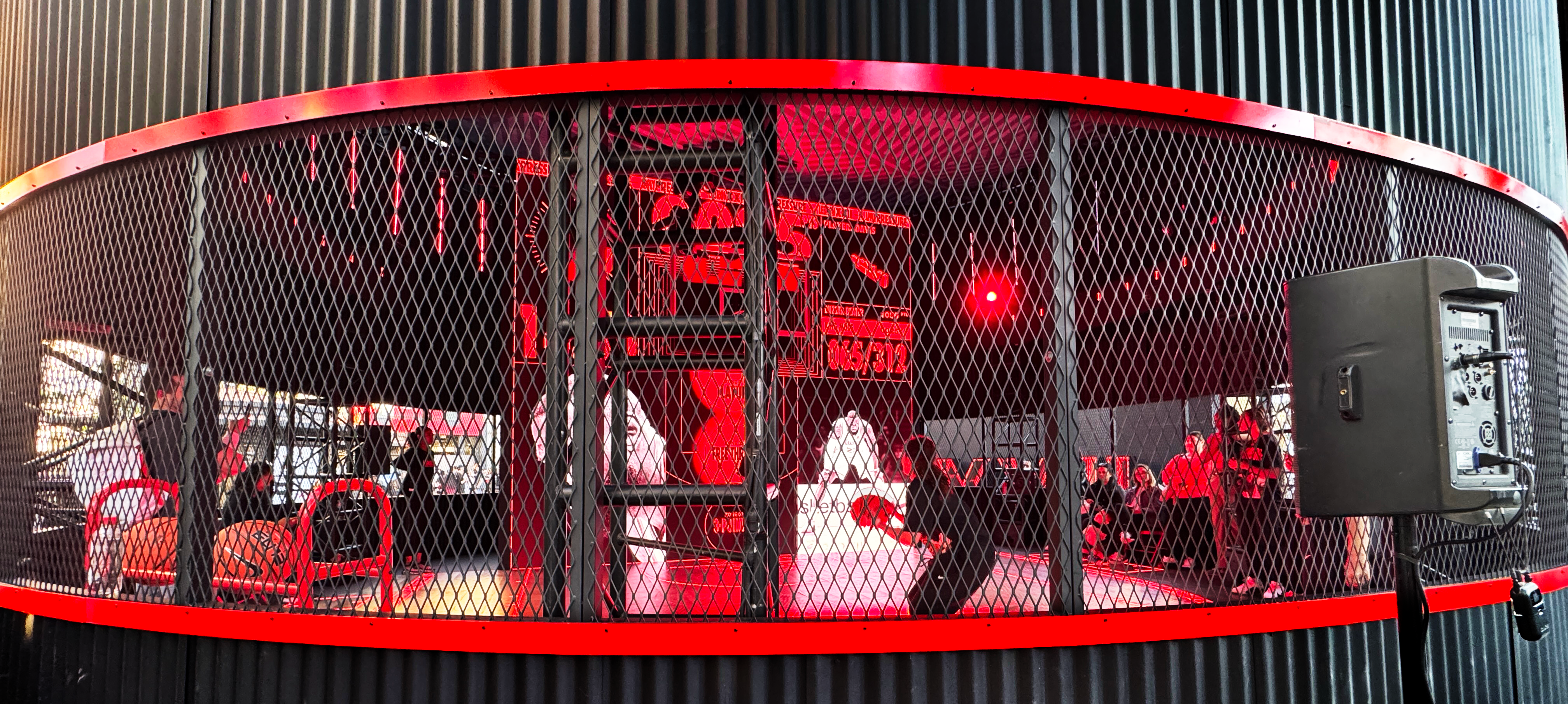 Red illuminated graphics and basketball displays behind a curved mesh enclosure at the LeBron experience.