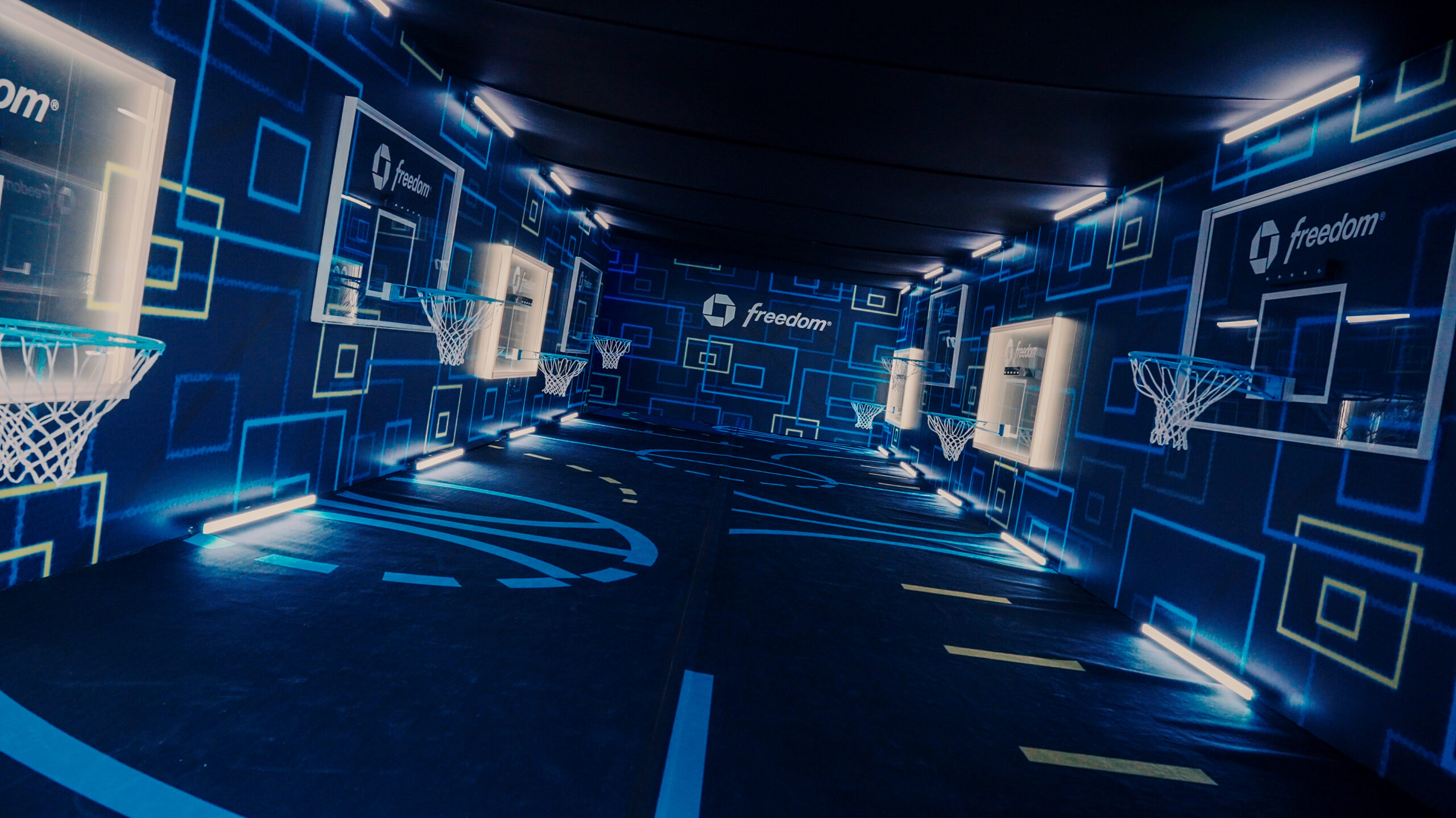 Multiple Chase Freedom basketball hoops inside a room of blue illuminated graphics.
