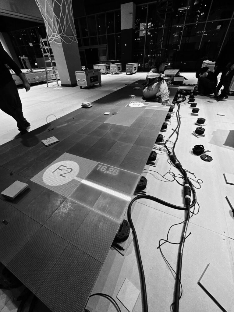 A black-and-white view of basketball court equipment and cabling during installation.
