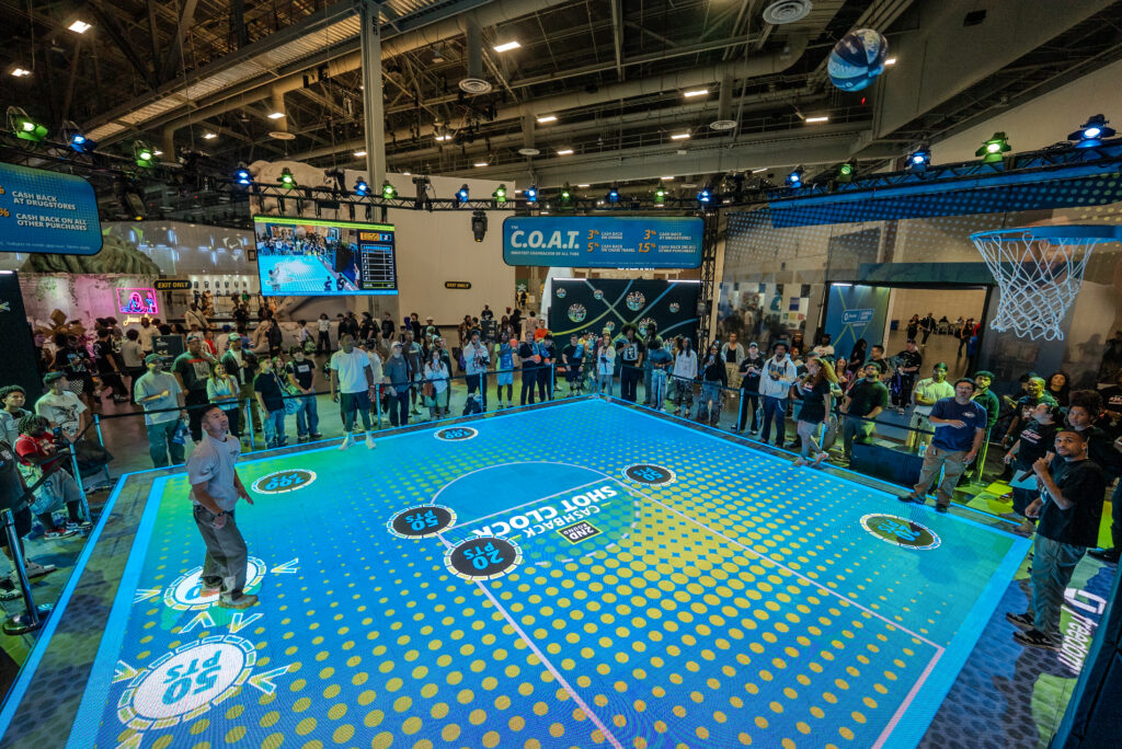 Visitors watch a player on the illuminated blue and green Chase basketball court.