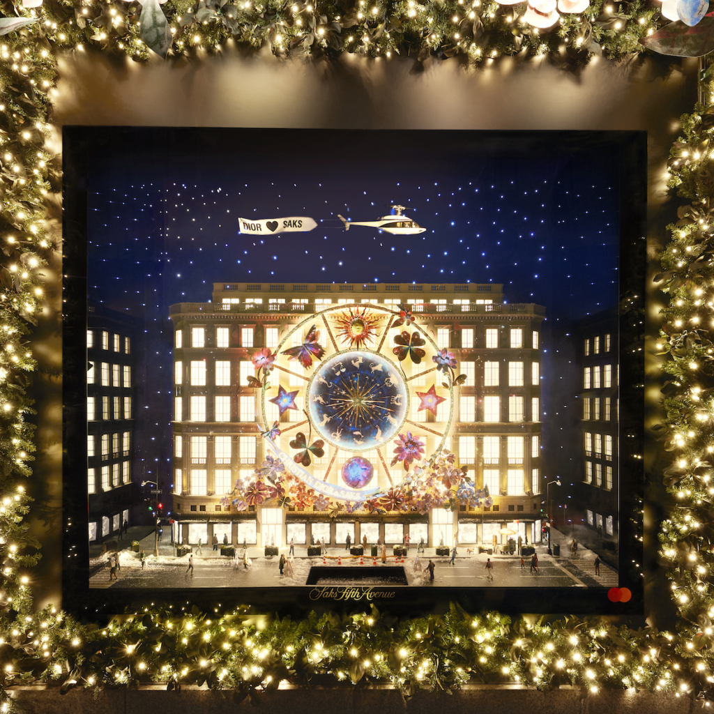 A Dior holiday window depicts an illuminated building beneath a starry sky.