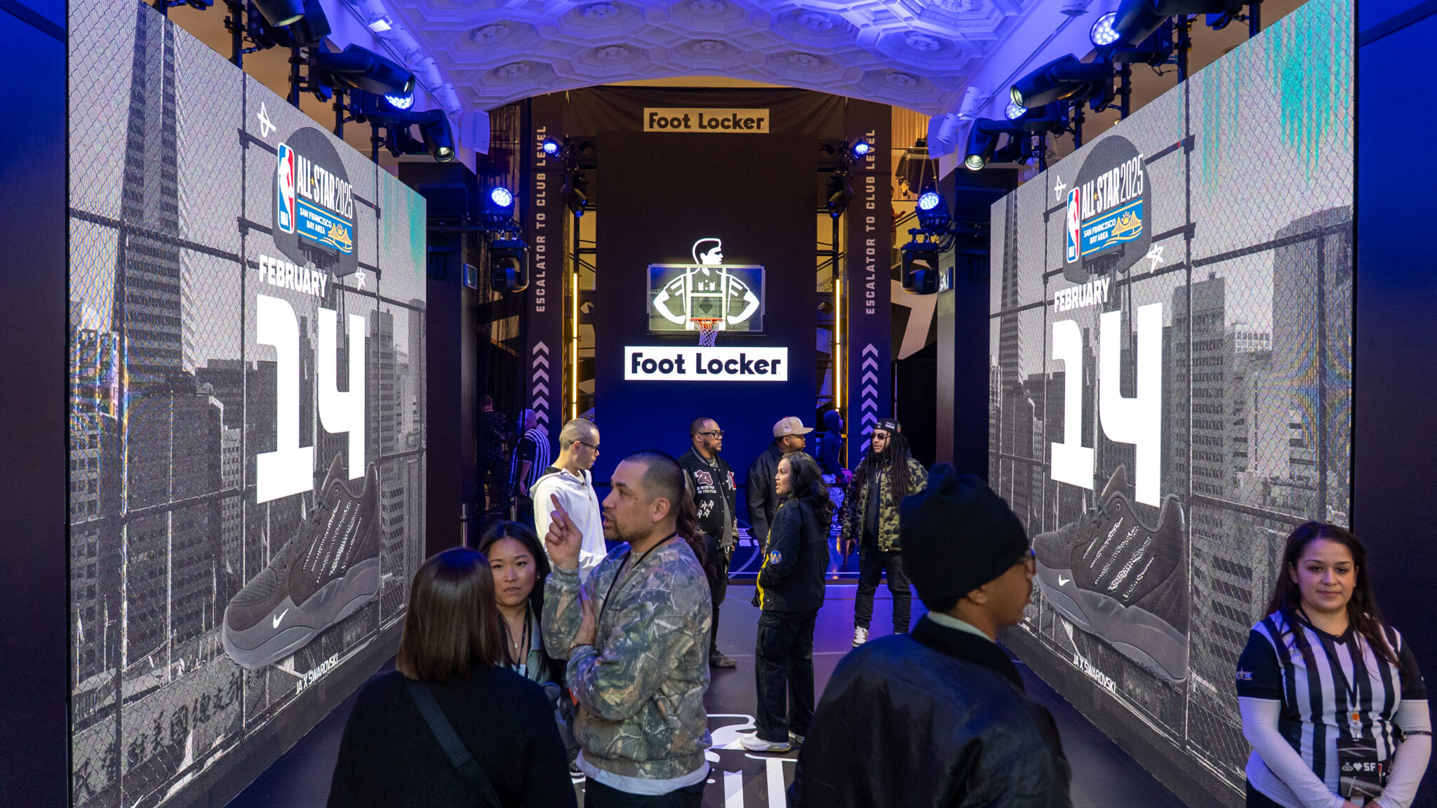 Visitors stand between tall Foot Locker displays showing basketball imagery.