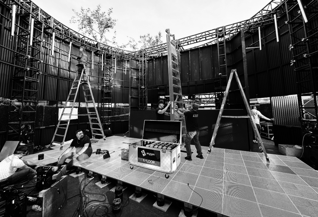 A black-and-white view of workers, ladders and display structures during installation.