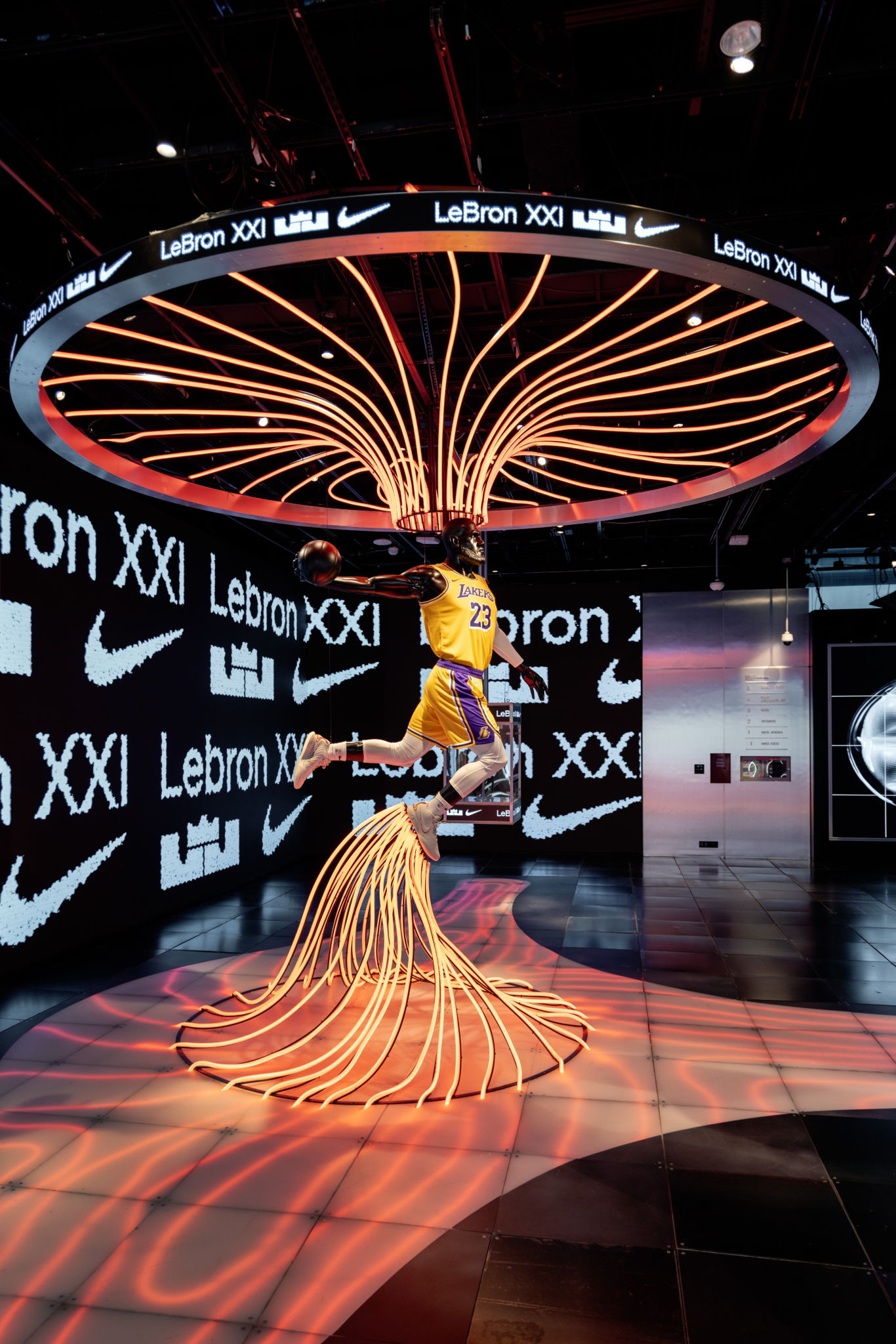 A suspended circular display above an illuminated basketball figure in the Nike installation.