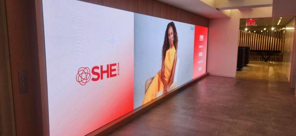A wide digital display shows fashion imagery in the Penske Media Corporation interior.