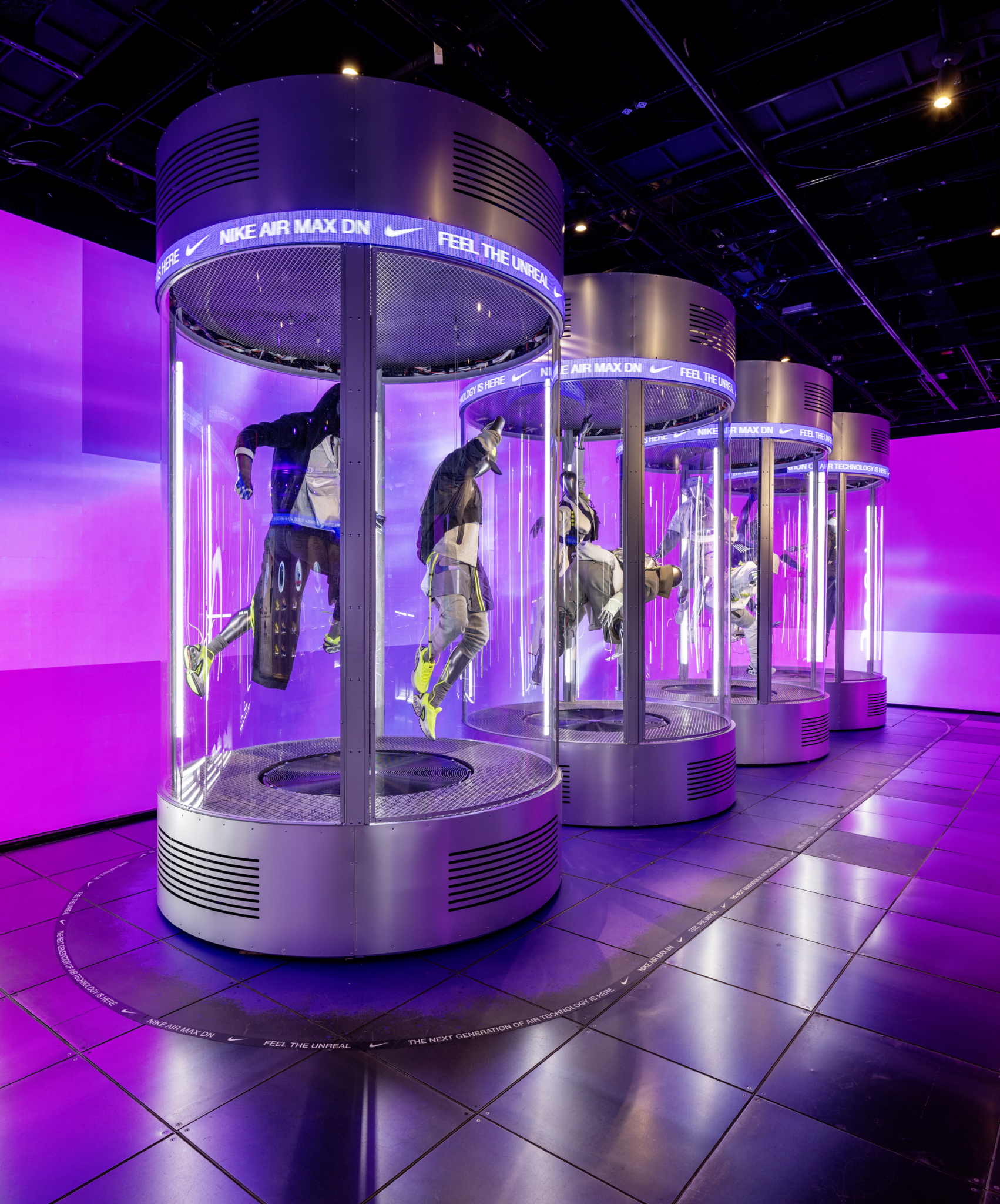 A cylindrical illuminated shoe display in the purple-lit Nike AirMax installation.