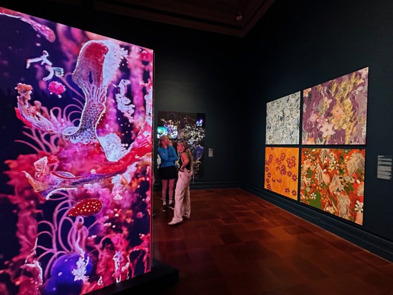 Visitors view colorful illuminated artwork in the Infinite Images exhibition.