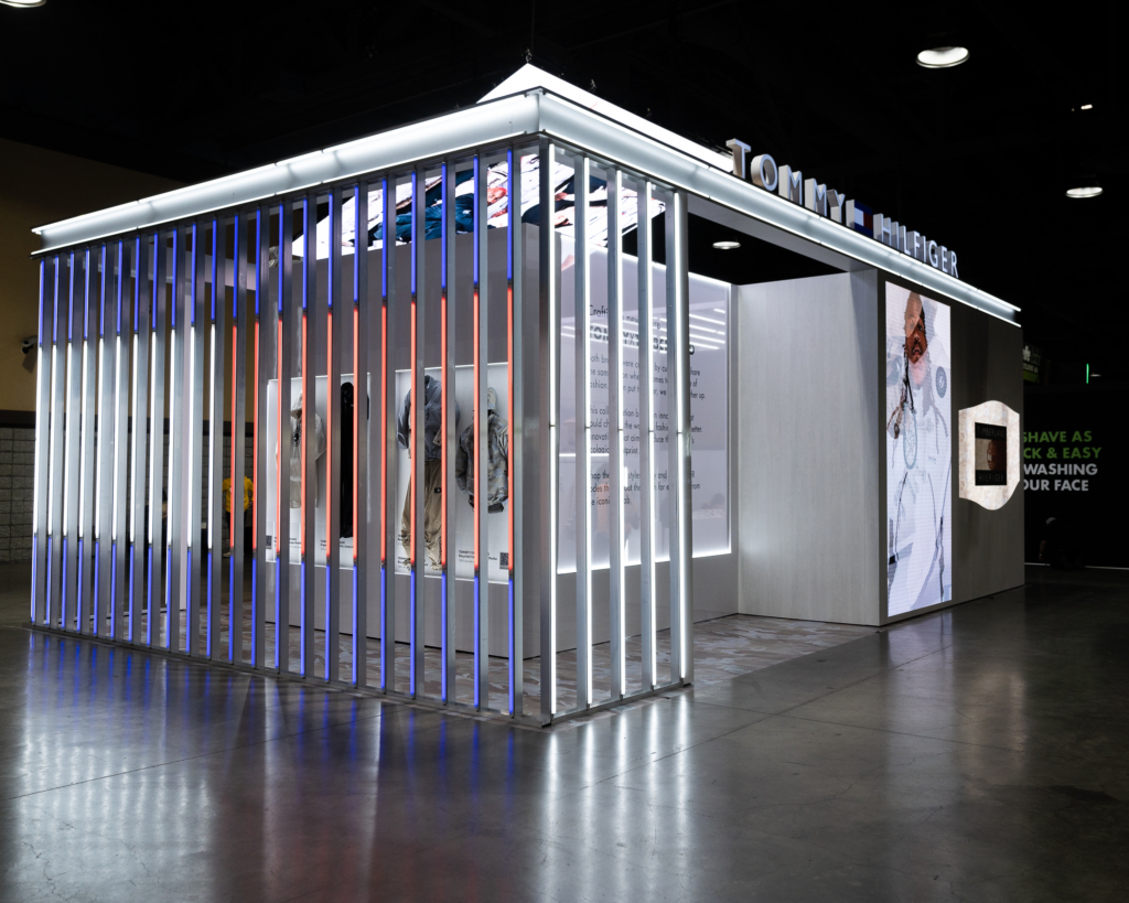 A side view of the Tommy Hilfiger pavilion with illuminated vertical bars and digital imagery.
